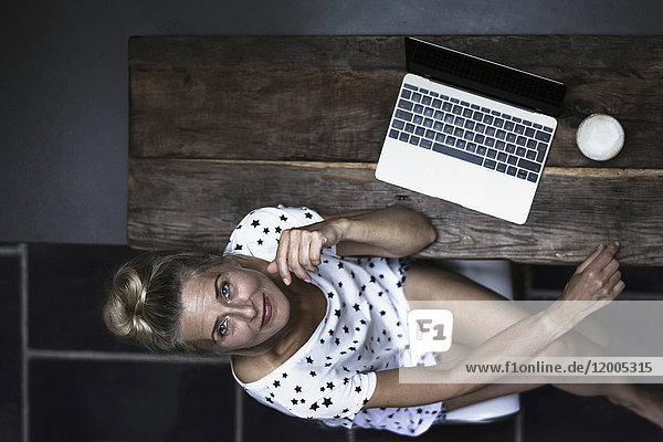 Woman sitting in kitchen  using laptop