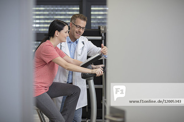 Smiling doctor and patient on exercise machine