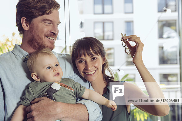 Happy couple with baby holding house key