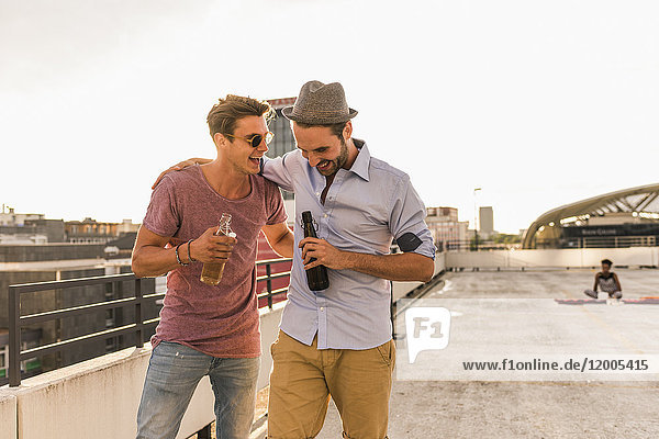 Two friends with beer bottles on rooftop