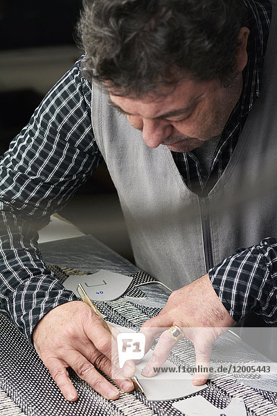 Schuhmacher bei der Arbeit an der Schablone in seiner Werkstatt