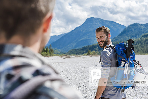 Deutschland  Bayern  Porträt eines jungen Wanderers mit Rucksack und Blick auf seinen Freund