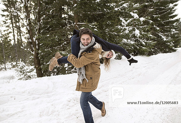 Happy young couple having fun in snow-covered winter landscape