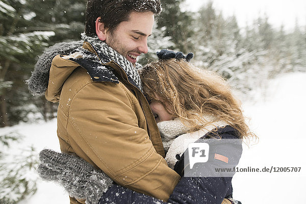 Happy young couple having fun in snow-covered winter forest