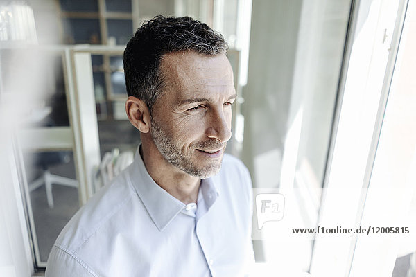 Smiling businessman looking out of window