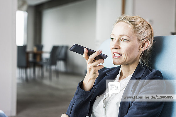 Geschäftsfrau  die ein Handy benutzt  um Voicemail zu versenden.