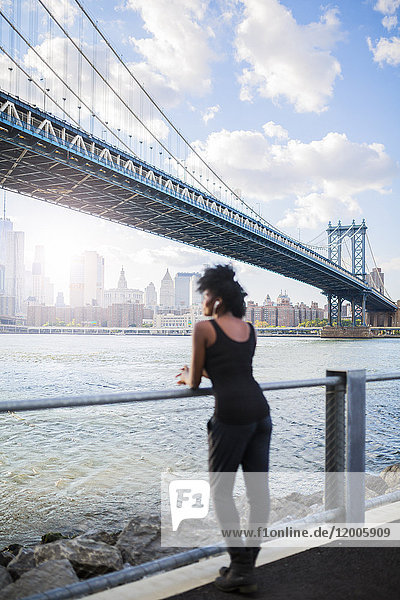 USA  New York City  Brooklyn  Frau hört Musik in der Nähe von Manhattan Bridge