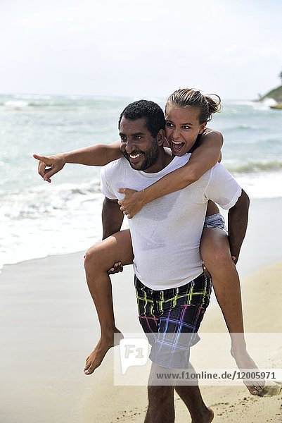 Man giving girlfriend piggyback ride on the beach