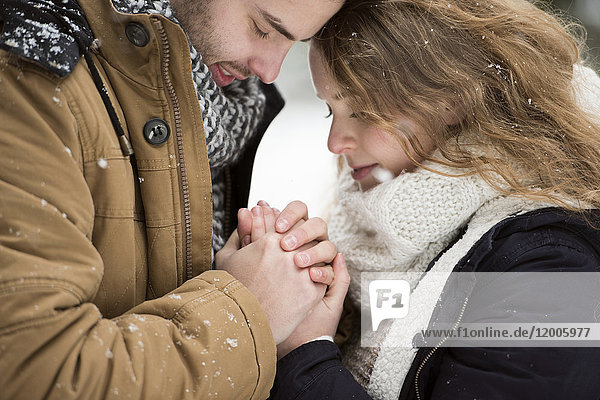 Ein glückliches junges Paar hält sich an den Händen.