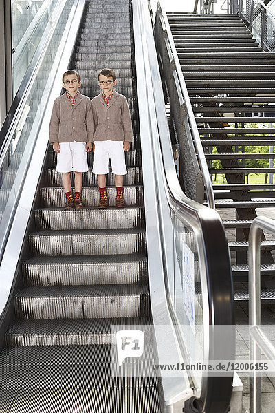 Zwillingsbrüder auf Rolltreppe stehend