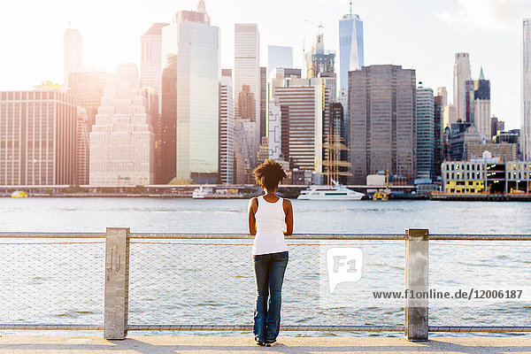 USA  New York City  Brooklyn  Frau am Wasser mit Blick auf die Skyline