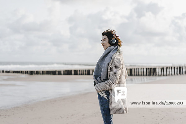 Frau am Strand stehend mit Kopfhörer