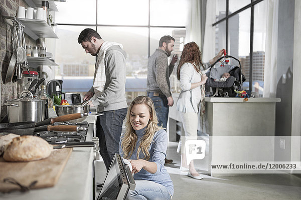 Paar beim Kochen in der Küche mit der Familie im Hintergrund