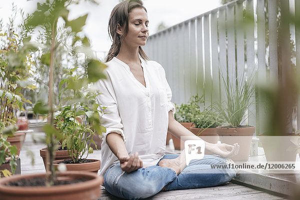 Frau sitzt auf dem Balkon und praktiziert Yoga