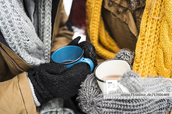 Junges Paar mit Handschuhen und Tassen Tee im Winter  Nahaufnahme