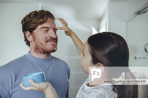 Daughter putting facial cream on father?s face