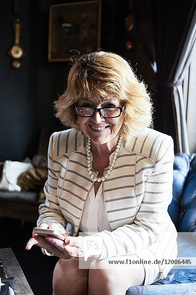 Porträt einer lächelnden Senior-Geschäftsfrau mit Handy