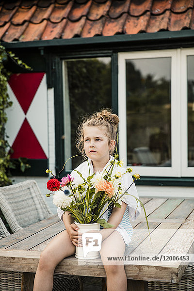 Mädchen mit Blumenstrauß auf dem Terrassentisch