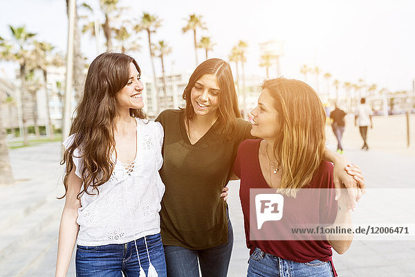 Drei glückliche Freundinnen beim Spaziergang auf der Strandpromenade