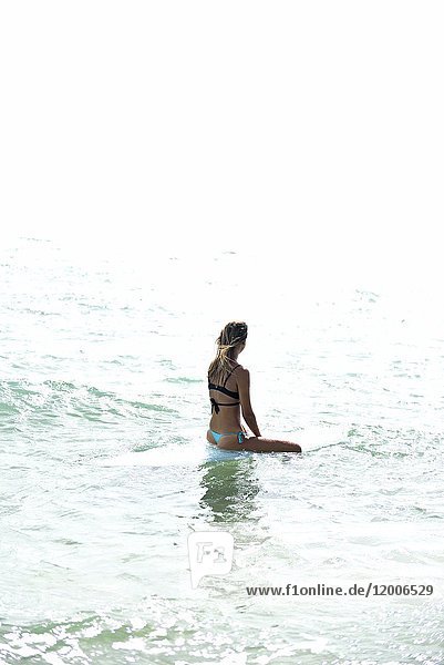 Frau sitzt auf dem Surfbrett im Meer