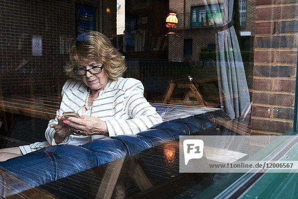 Senior businesswoman checking cell phone in a coffee shop