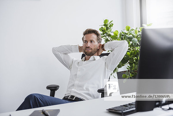 Porträt eines Geschäftsmannes  der sich am Schreibtisch in seinem Büro entspannt.