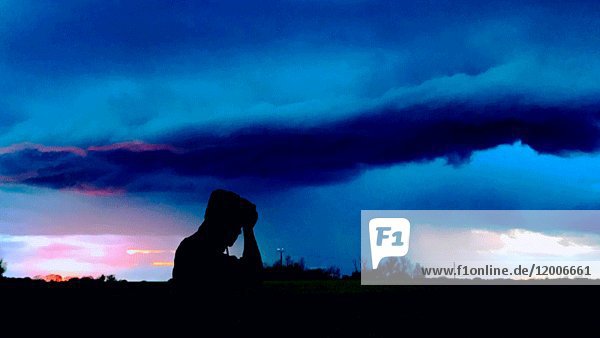 Silhouette eines Mannes auf einem Feld  während sich ein Sturm nähert