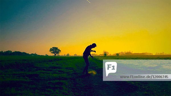 Mann wirbelt Staub auf einem Feld auf  während ein Flugzeug über ihn hinwegfliegt