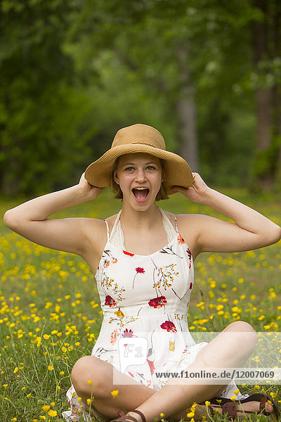 Surprised Caucasian teenage girl sitting in field of flowers