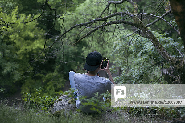 Kaukasischer Mann  der im Wald eine SMS auf seinem Mobiltelefon schreibt