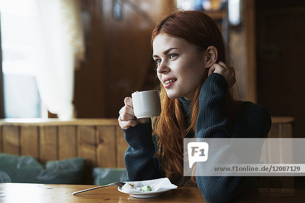 Lächelnde Frau trinkt Kaffee in einem Cafe