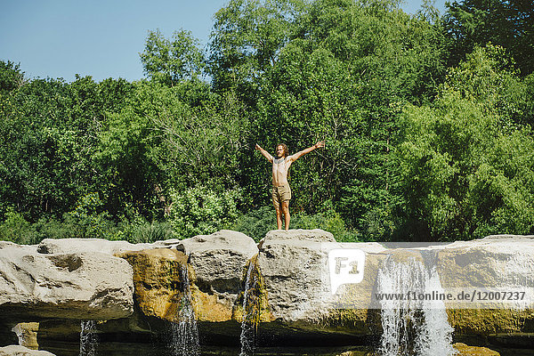 Kaukasischer Mann steht auf Felsen in der Nähe von Wasserfällen