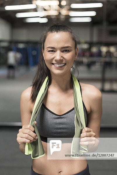 Smiling mixed race woman holding towel in gymnasium