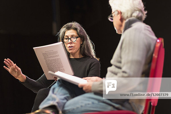 Hispanic man and woman reading scripts on theater stage