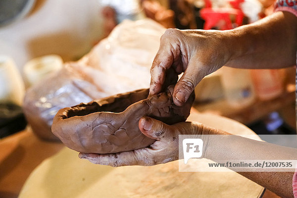 Die Hände einer gemischtrassigen Frau formen Ton in einem Kunstatelier