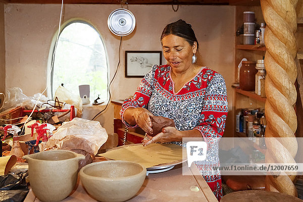 Mixed race woman shaping clay in art studio