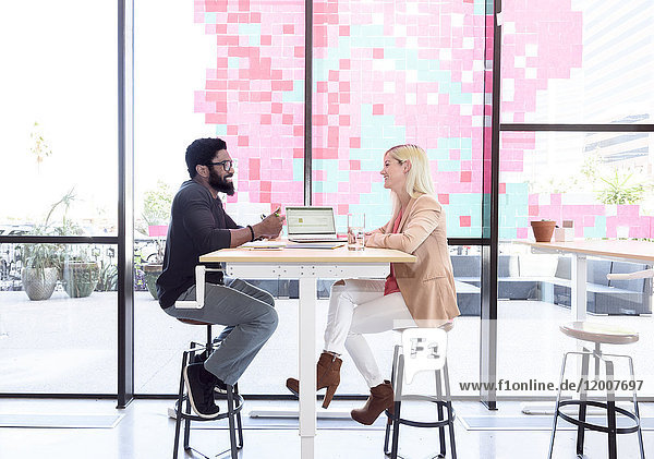 Kreative Geschäftsleute im Gespräch am Tisch mit Laptop
