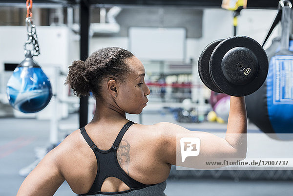 Black woman lifting dumbbell in gymnasium