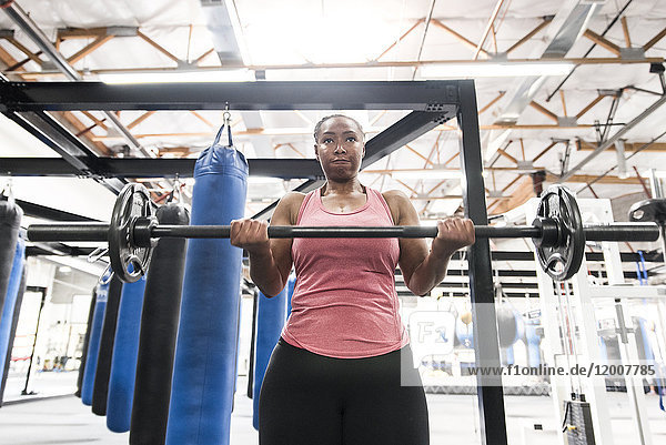 Black woman lifting barbell in gymnasium