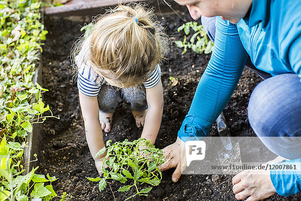 Kaukasische Mutter bringt ihrer Tochter Gartenarbeit bei
