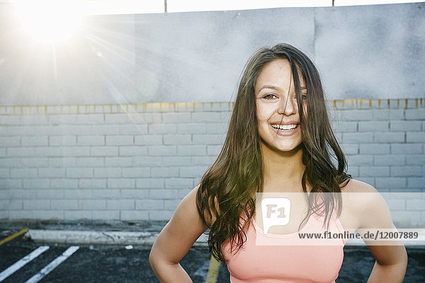Sunbeams on smiling mixed race woman in parking lot