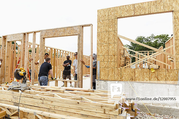 Volunteers holding framed wall at construction site