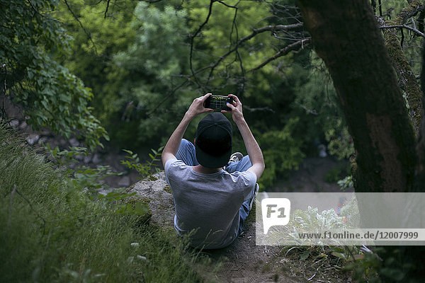 Kaukasischer Mann fotografiert mit Handy im Wald