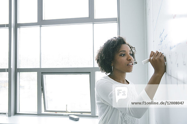Afroamerikanische Geschäftsfrau schreibt in einer Besprechung auf eine Tafel