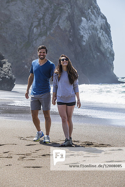 Paar hält Hände und geht am Strand spazieren