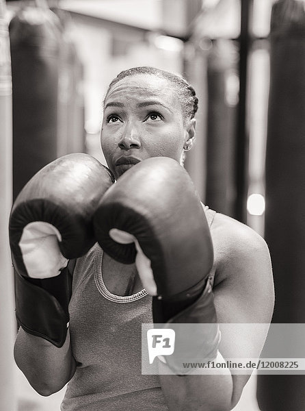 Portrait of Black woman wearing boxing gloves looking up