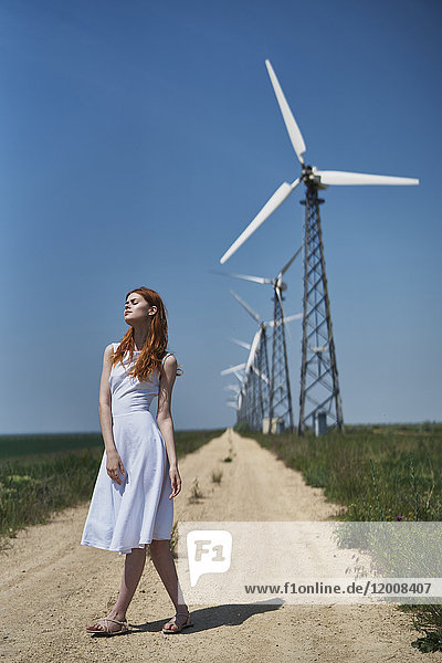 Caucasian woman on dirt path near wind turbines