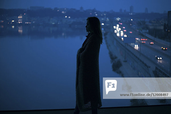 Kaukasische Frau steht nachts in der Nähe des Ufers