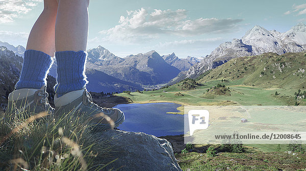 Beine einer kaukasischen Frau  die auf einem Felsen über einem See im Tal steht