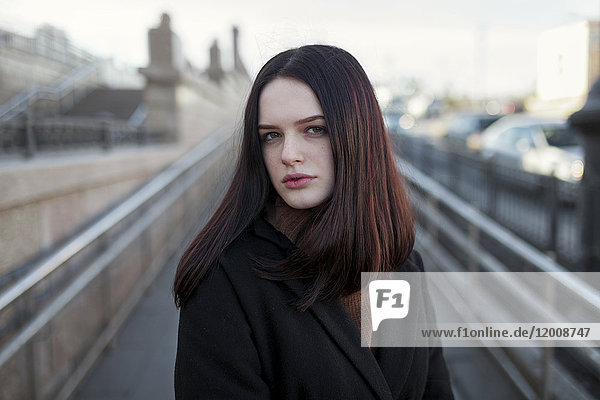 Serious Caucasian girl standing on footbridge